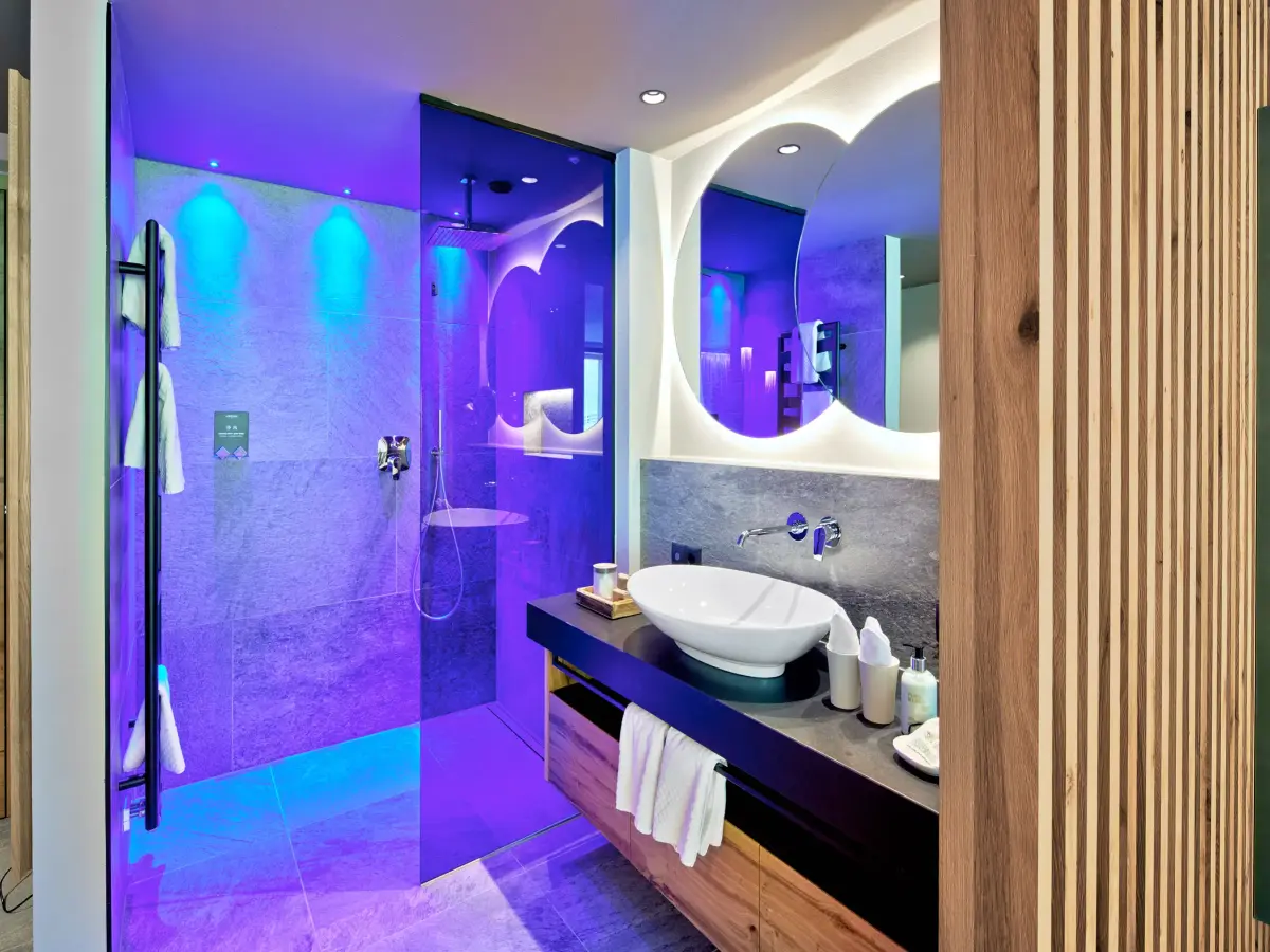 Bagno dell'hotel nelle Alpi con fondo Lacryl e installazione luminosa colorata.