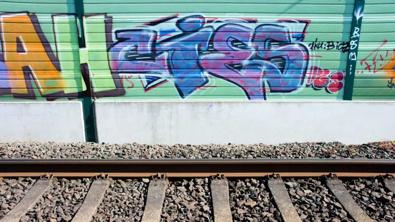Graffiti an der Wand und Bahnschienen