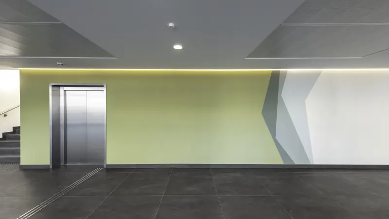 Eingangsbereich Klinik mit gelber Wand und Fahrstuhl