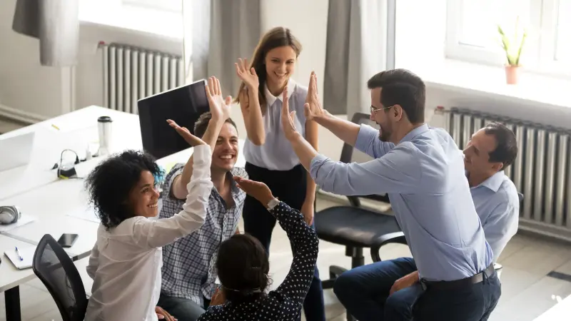 Mehrere Personen in einem Büroumfeld geben sich ein High-Five