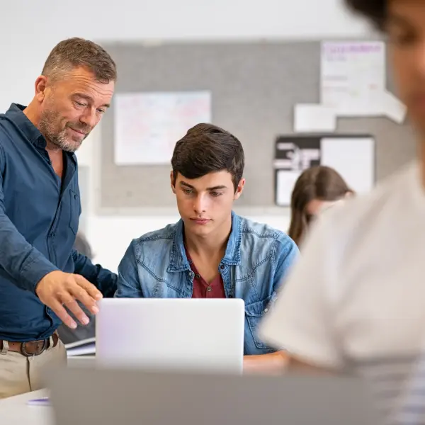 Ein Berufsschullehrer lehrt einen Schüler am Laptop