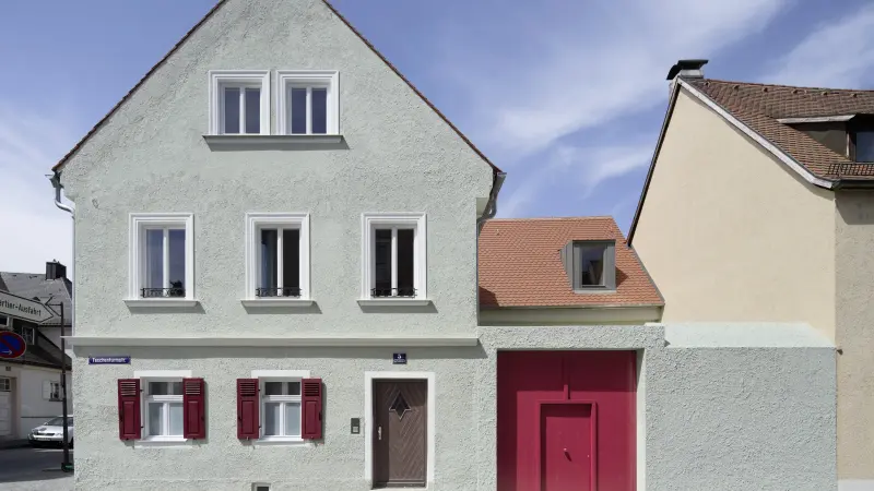 Thürwachterhaus von vorne mit grüner Fassade und einem roten Tor