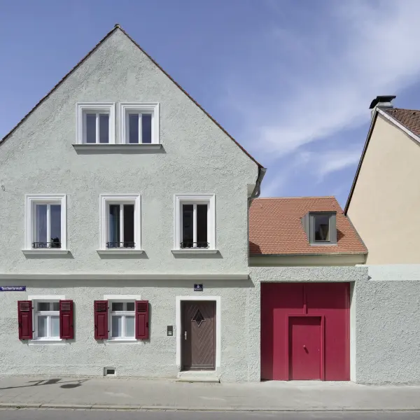 Thürwachterhaus von vorne mit grüner Fassade und einem roten Tor
