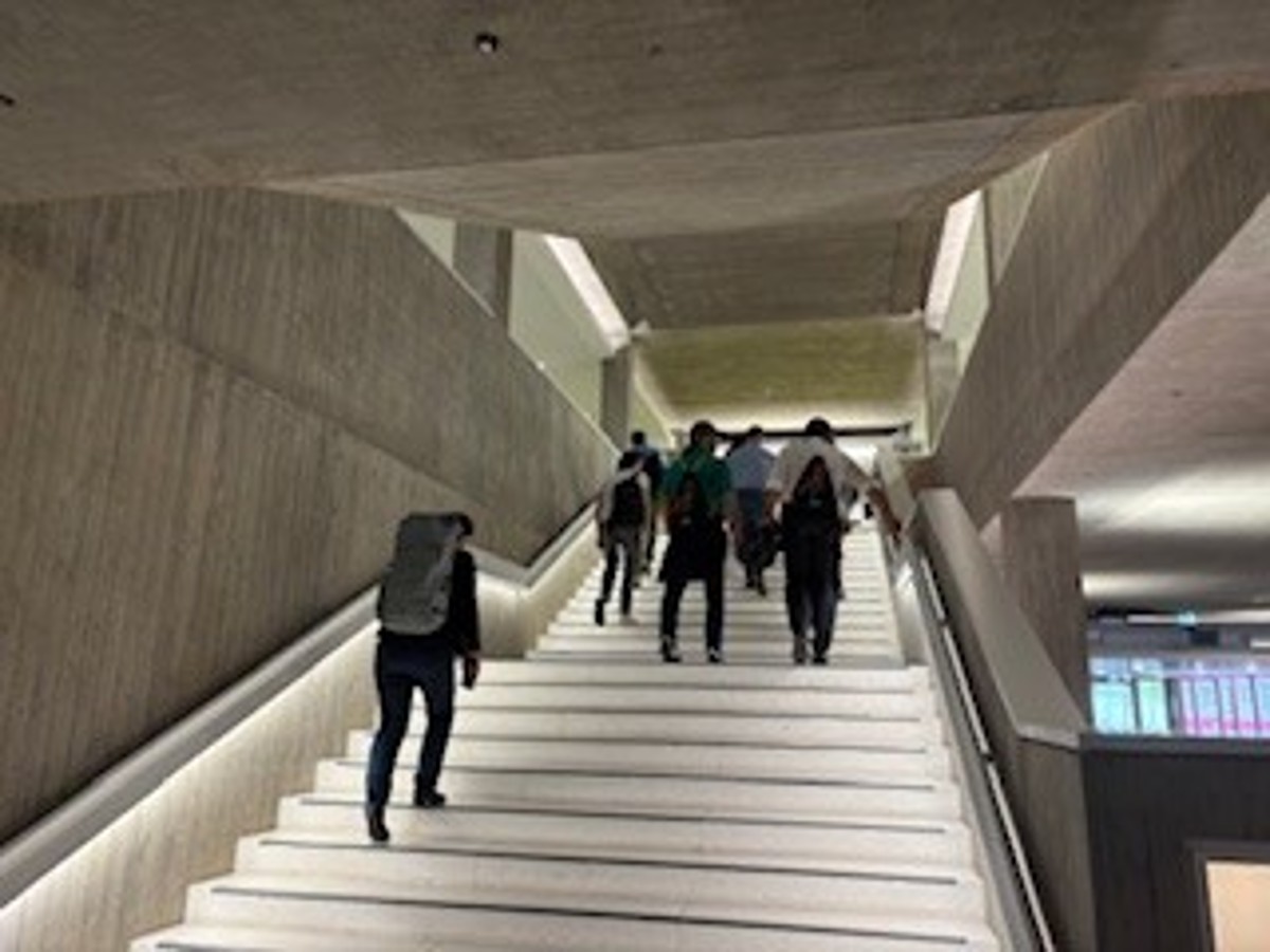 Eine Gruppe von Menschen geht eine beleuchtete Treppe hinauf. 