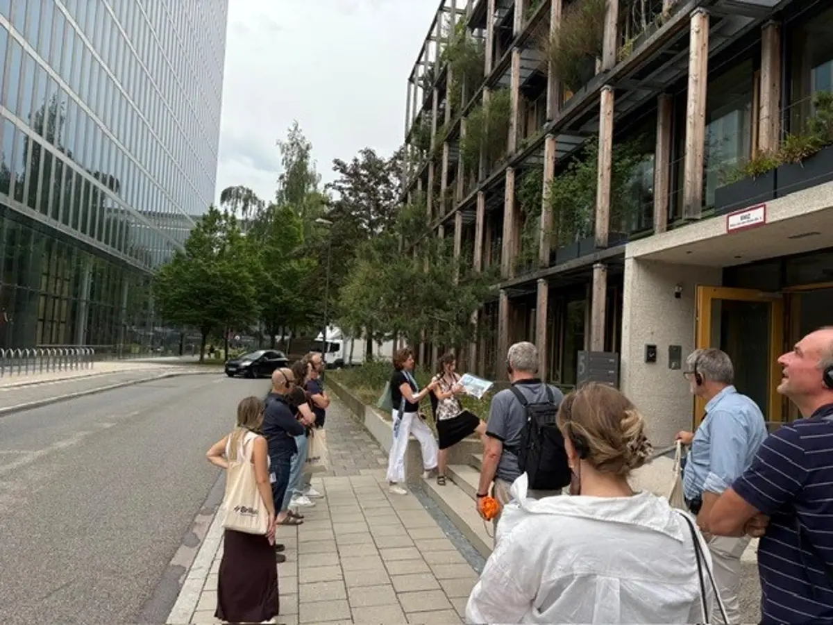 Eine Gruppe von Menschen mitten in München vor einem hohen Glasgebäude