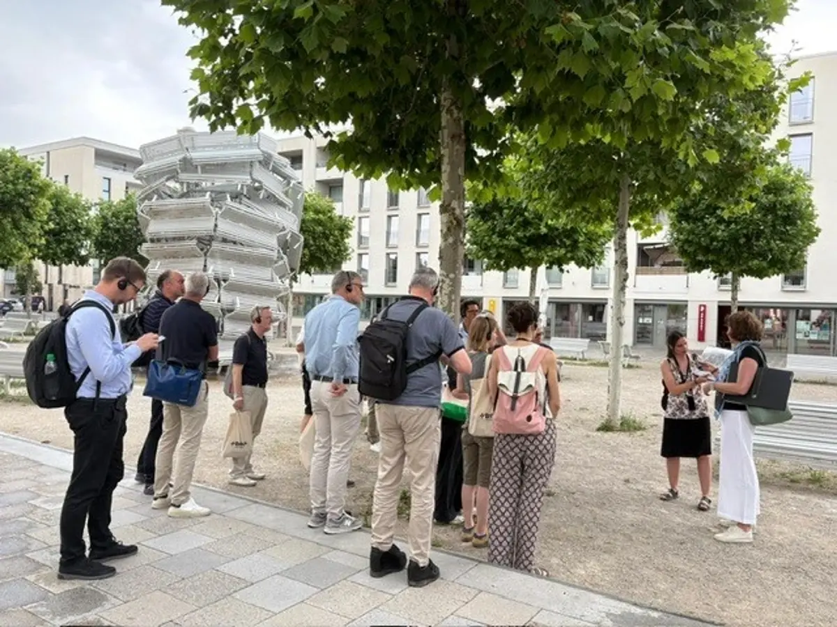 Eine Gruppe von Menschen hört einem Vortrag im Park zu.