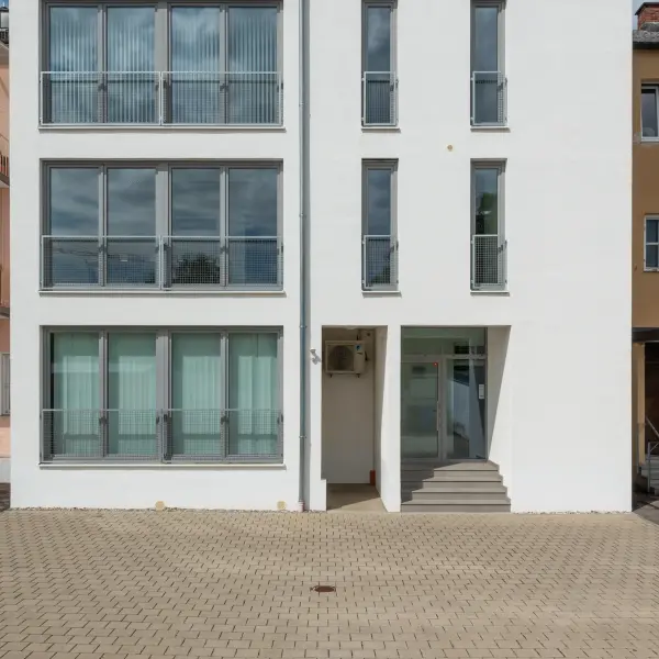 Haus mit oben grauer und unten weißer Fassade und großen Fenstern