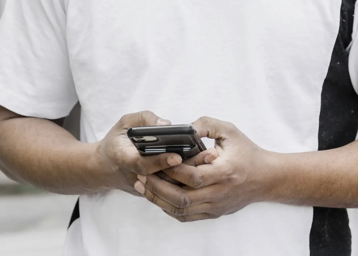 Ein Person mit weißem T-Shirt tippt auf einem Smartphone