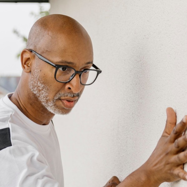 Eine Farbrolle streicht auf einer Fassade