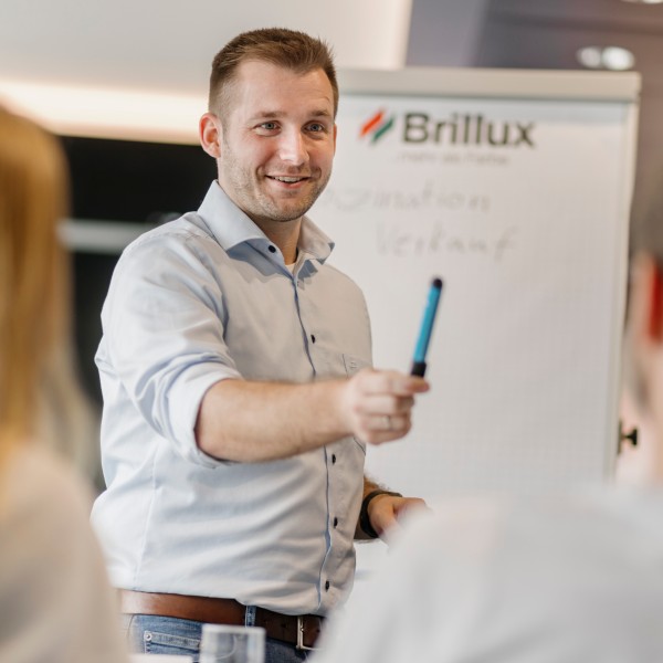 Ein Mann hält eine Präsentation und reicht einem Zuschauer einen Stift.