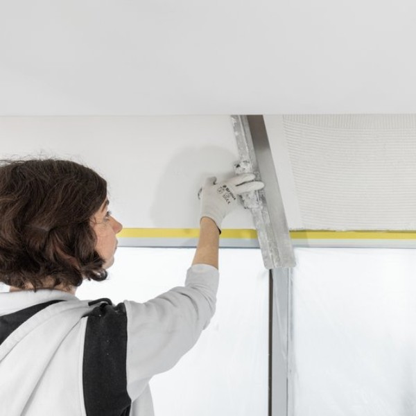 Eine Malerin spachtelt eine Decke