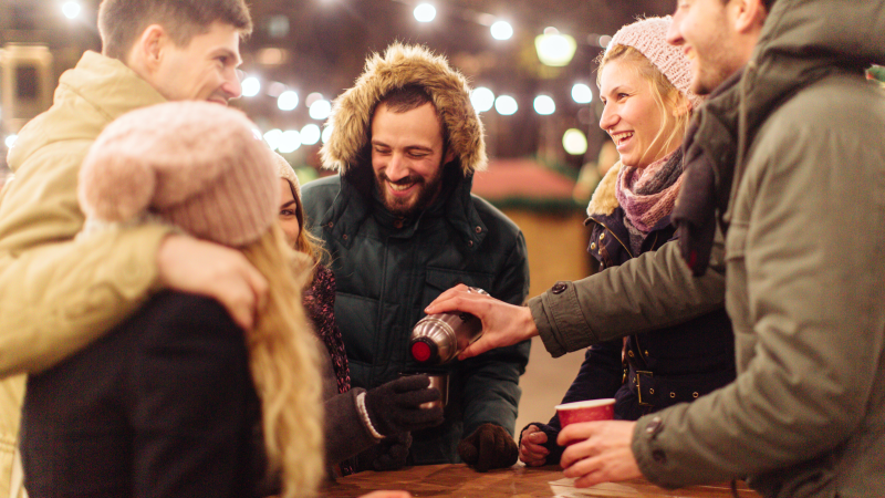 Gruppe von Menschen in dicken Jacken gekleidet mit Glühwein