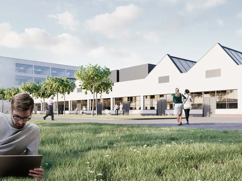 Junger Mann mit Laptop vor dem Campus