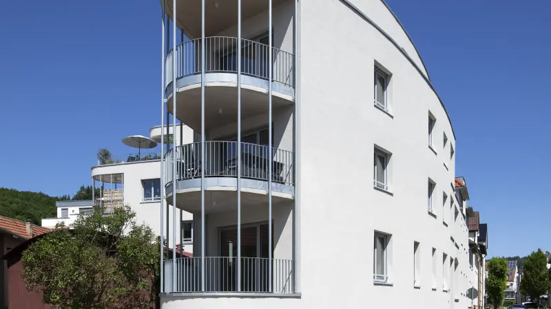 Großes weißes Haus in organischer Form mit offenen Balkonen