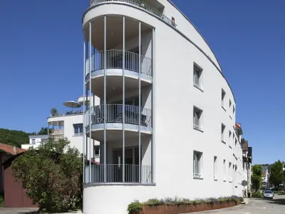 Großes weißes Haus in organischer Form mit offenen Balkonen