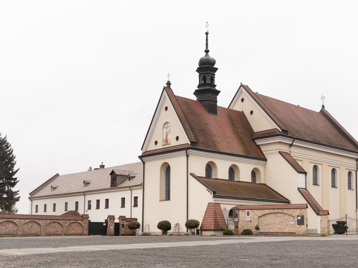  Klosterkirche in Polen, mit hellen Mauern, rotem Ziegeldach und einem hohen Glockenturm.