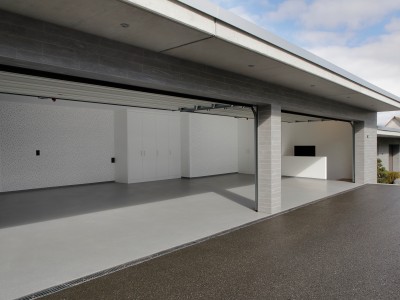 Moderne Doppelgarage mit geöffneten Toren, weißen Einbauschränken und grauem Boden.