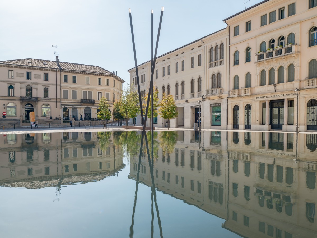 Ein Platz mit historischen Gebäuden, die sich in einer großen Wasserfläche spiegeln.
