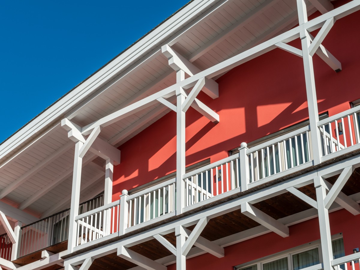 Balkon Hotel Eden mit roter Wand und weißen Holzpfählern
