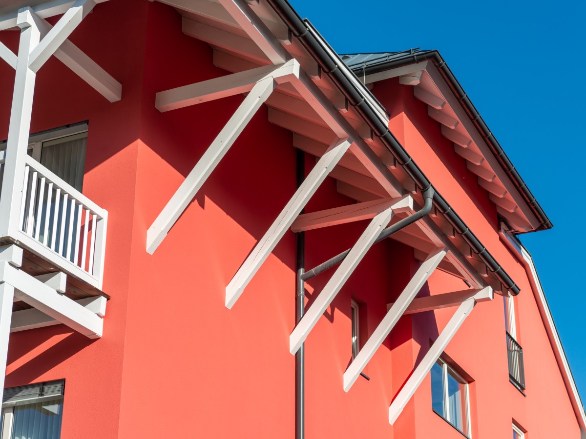 Rote Hauswand und weiße Holzpfähler