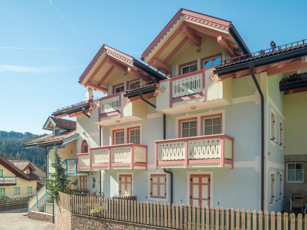 Ein traditionelles Haus im Alpenstil mit Balkonen und geschnitzten Verzierungen unter klarem blauem Himmel.