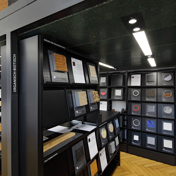 Mehrere schwarze Regale in einer Materialbibliothek zeigen Proben von organisch-biotischen Baumaterialien.