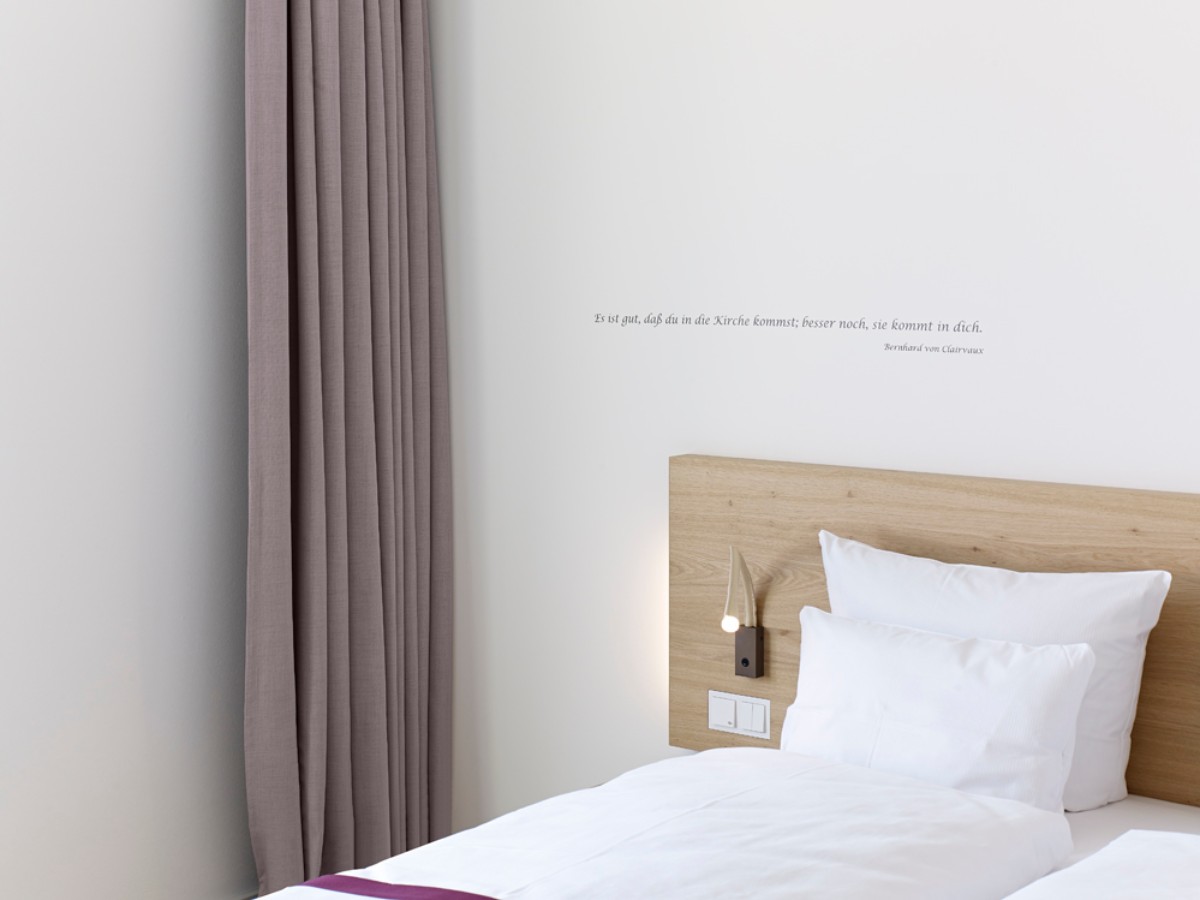 Schlafzimmerecke mit einem Zitat an der Wand über dem Bett