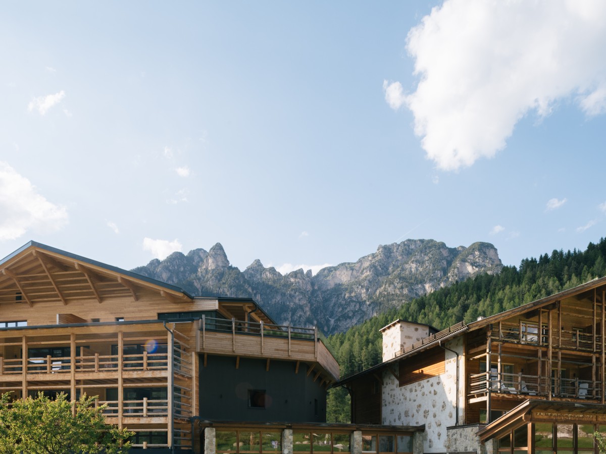Holzfassade eines Hotels in den Alpen mit blauem Himmel und Berg im Hintergrund