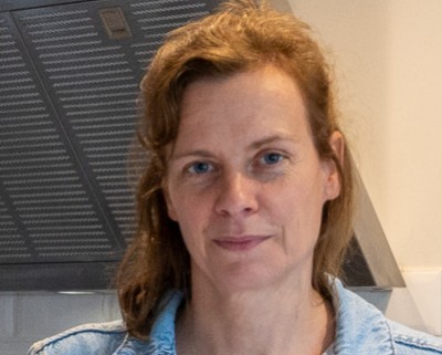 Frau vor grauer Küche und im Vordergrund ein weißer, runder Esstisch