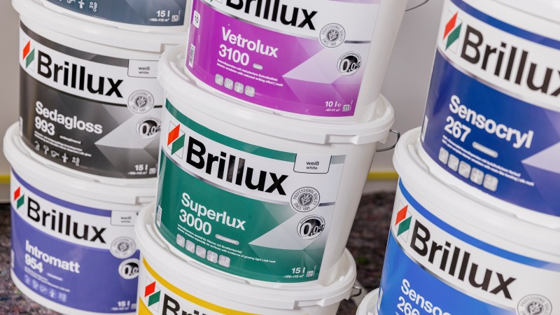 Gestapelte Brillux-Farbeimer mit Produktnamen wie Sedagloss, Superlux und Sensocryl.