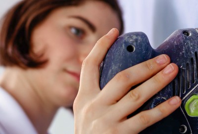 Frau mit Schleifmaschine an blauer Wand