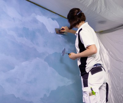 Frau mit Spachtel an blauer Wand