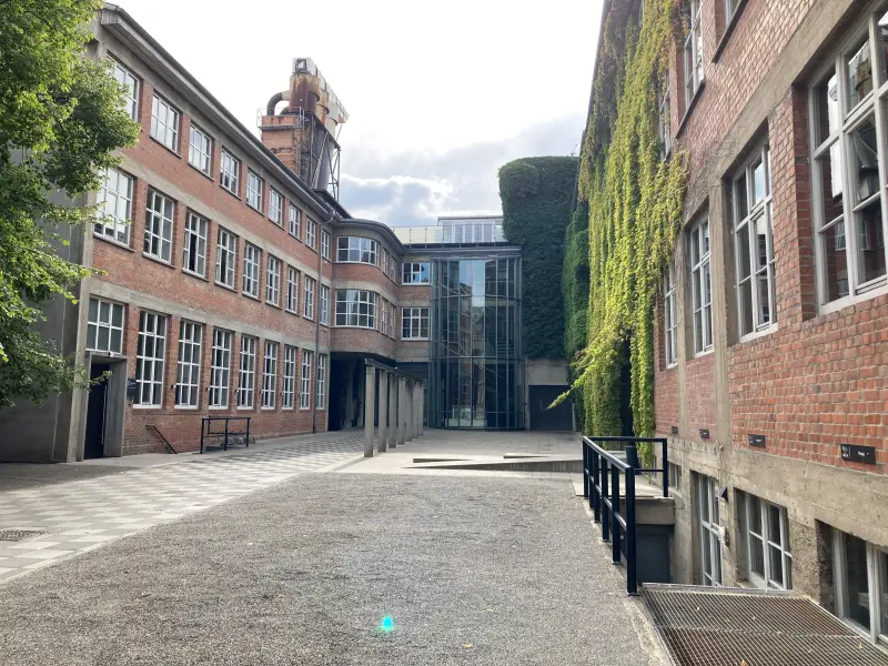 Großes Backsteingebäude mit viel Grün und einem großen Innenhof